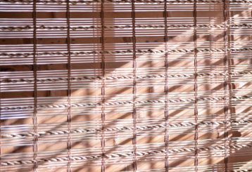 Chic Woven Wood Roman Shades installed on a living room window, adding natural warmth and style to the space.