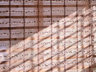 Chic Woven Wood Roman Shades installed on a living room window, adding natural warmth and style to the space.